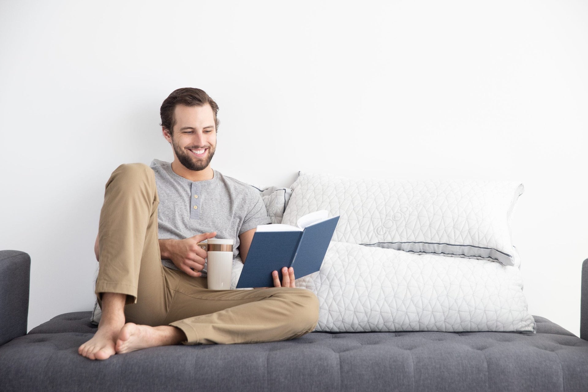 Man reading book and drinking tea in bed