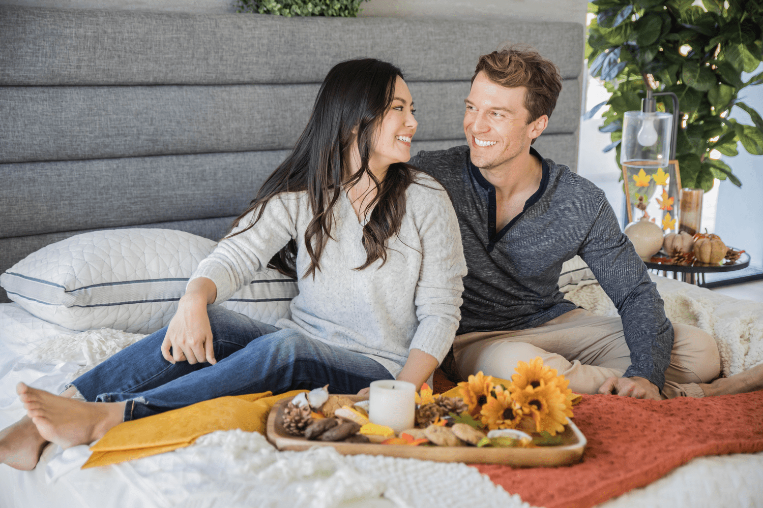 Couple smiling on bed with fall decor